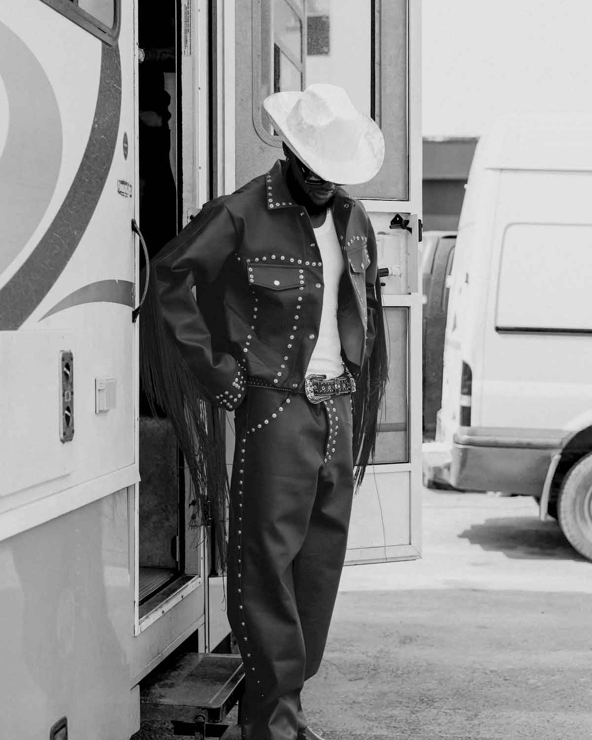 A man wearing studded punk  jacket and cowboy hat