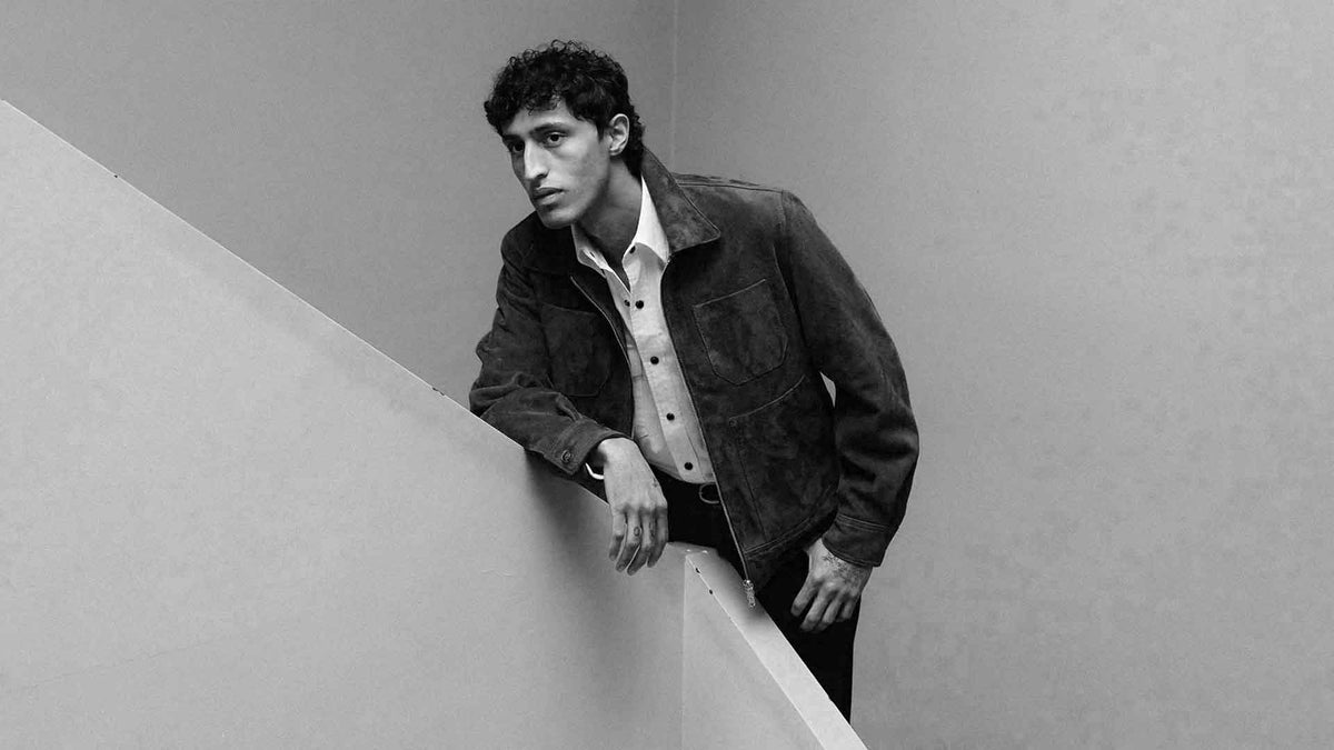 A man wearing a suede leather jacket over a white shirt