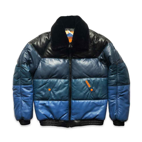 A color-blocked v bombeer jacket with a black leather upper chest and collar, a dark teal middle section, and a medium blue lower section, featuring a black fuzzy collar and black ribbed trim.
