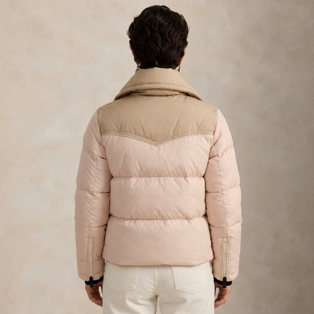A model shown from the back wearing a light beige and pale pink puffer jacket, paired with off-white trousers, against a textured beige studio background.