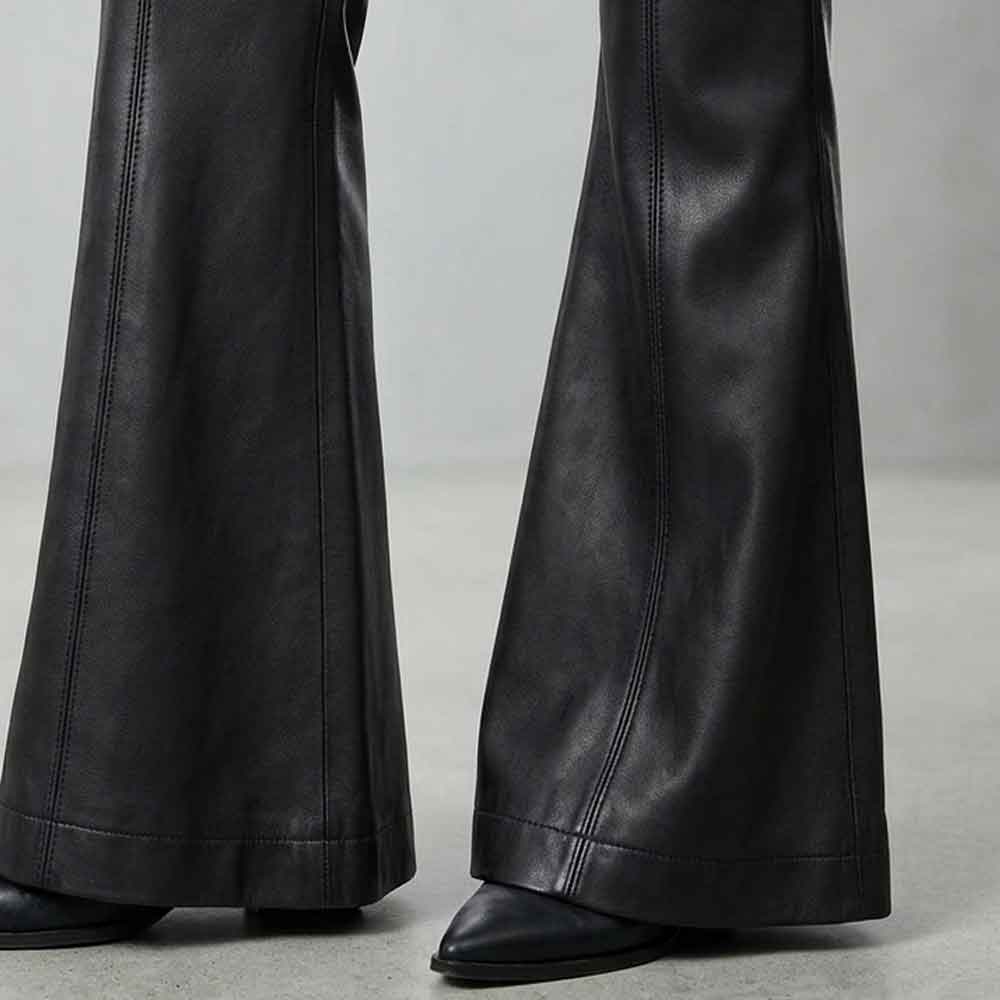 Black leather flare pants shown from the knees down, worn with black pointed-toe shoes on a light gray studio floor.