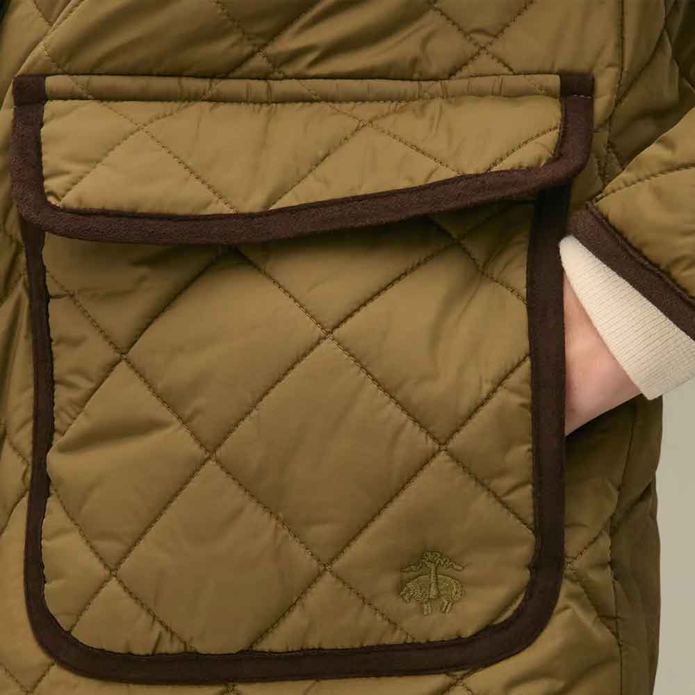 Close-up of a quilted olive green jacket pocket with dark brown trim with a sleeve and hand partially visible.