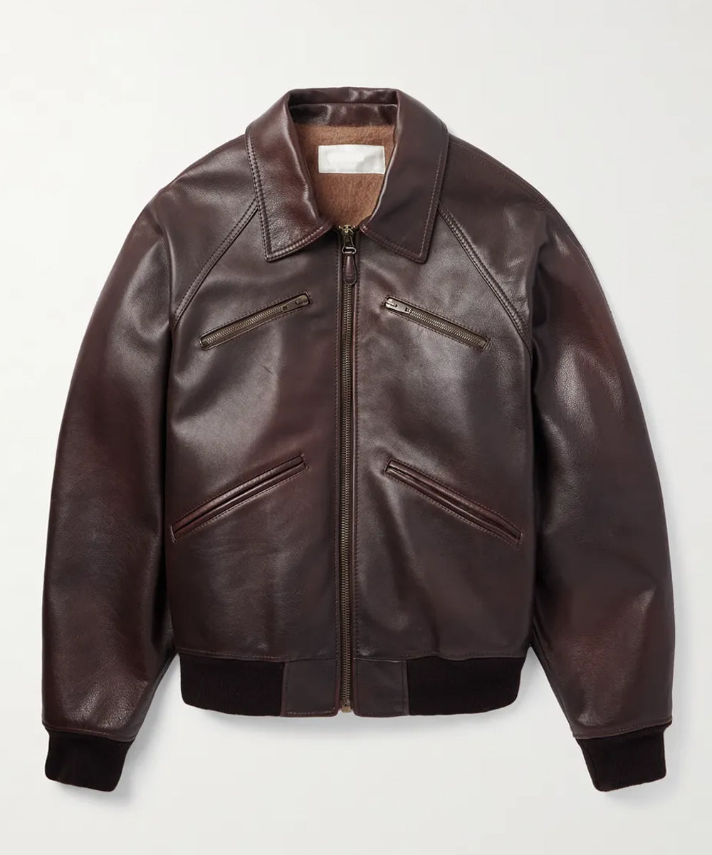 A dark brown Designer Leather Bomber Jacket with a front zipper, zippered chest pockets, and ribbed knit collar, cuffs, and hem, displayed on a light gray background.