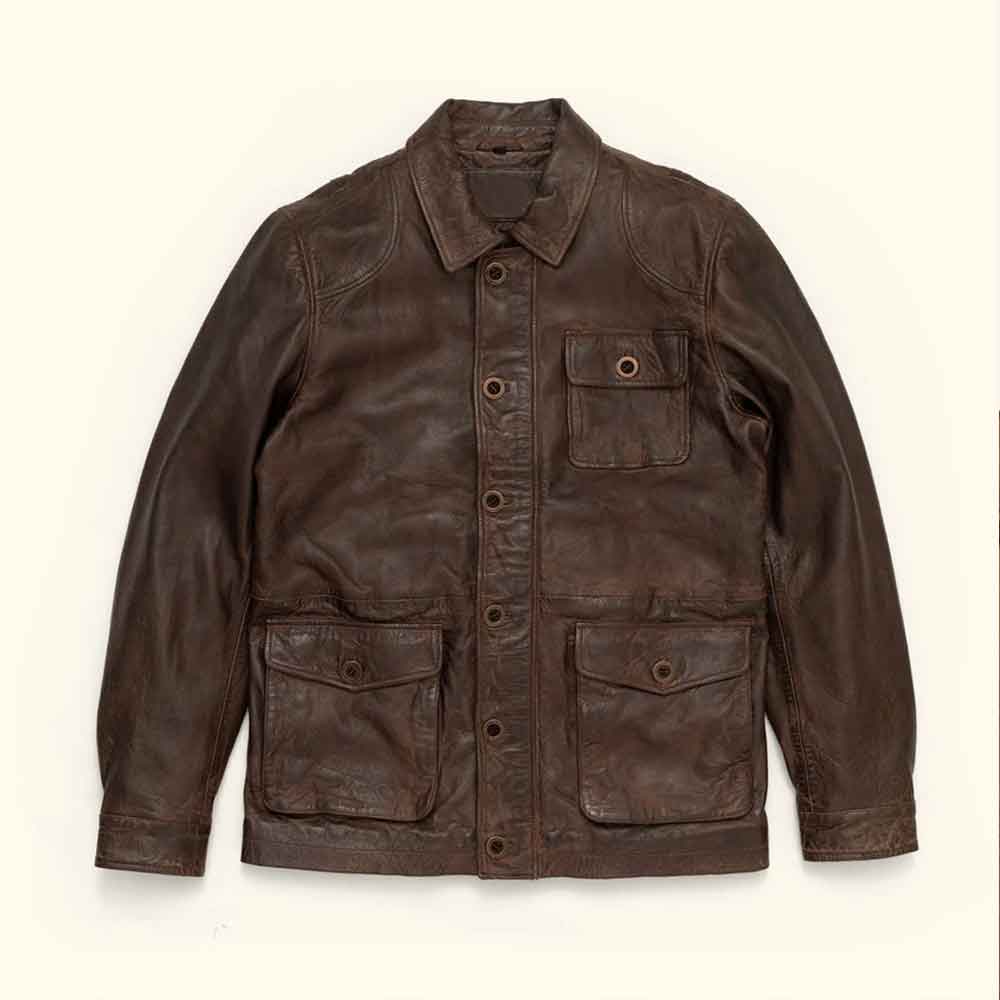 A dark brown Vintage Barn Jacket with a pointed collar, button-up front, and multiple front pockets, laid flat against a light cream background.