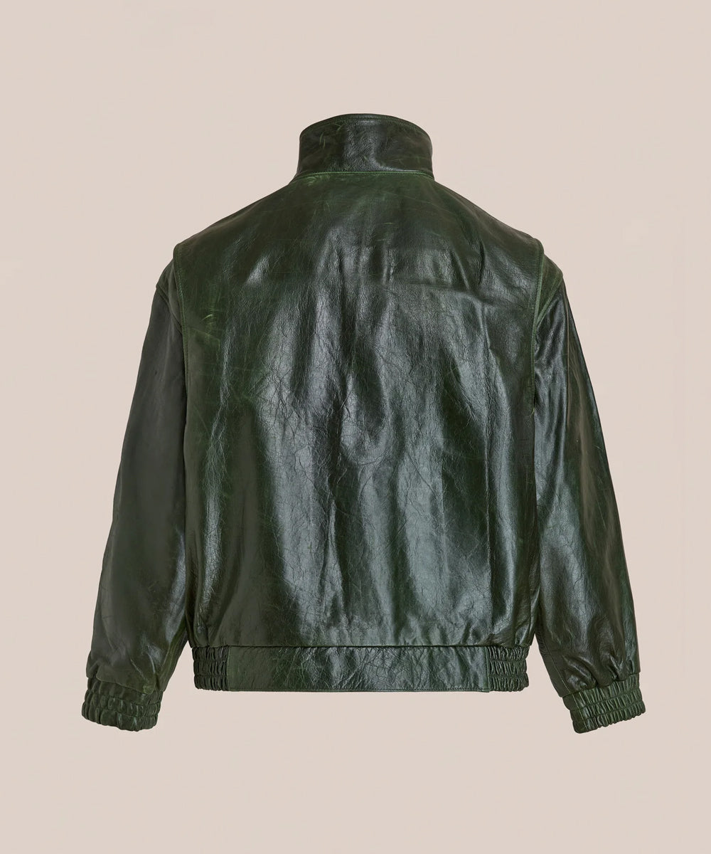 A dark forest green leather jacket shown from the back, featuring a high collar, smooth textured leather back panels, and contrasted with smooth dark green sleeves, set against a solid beige background.